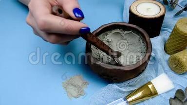 手用蓝色指甲修剪搅拌化妆品粘土面膜成分。 手工制作美容护肤面膜